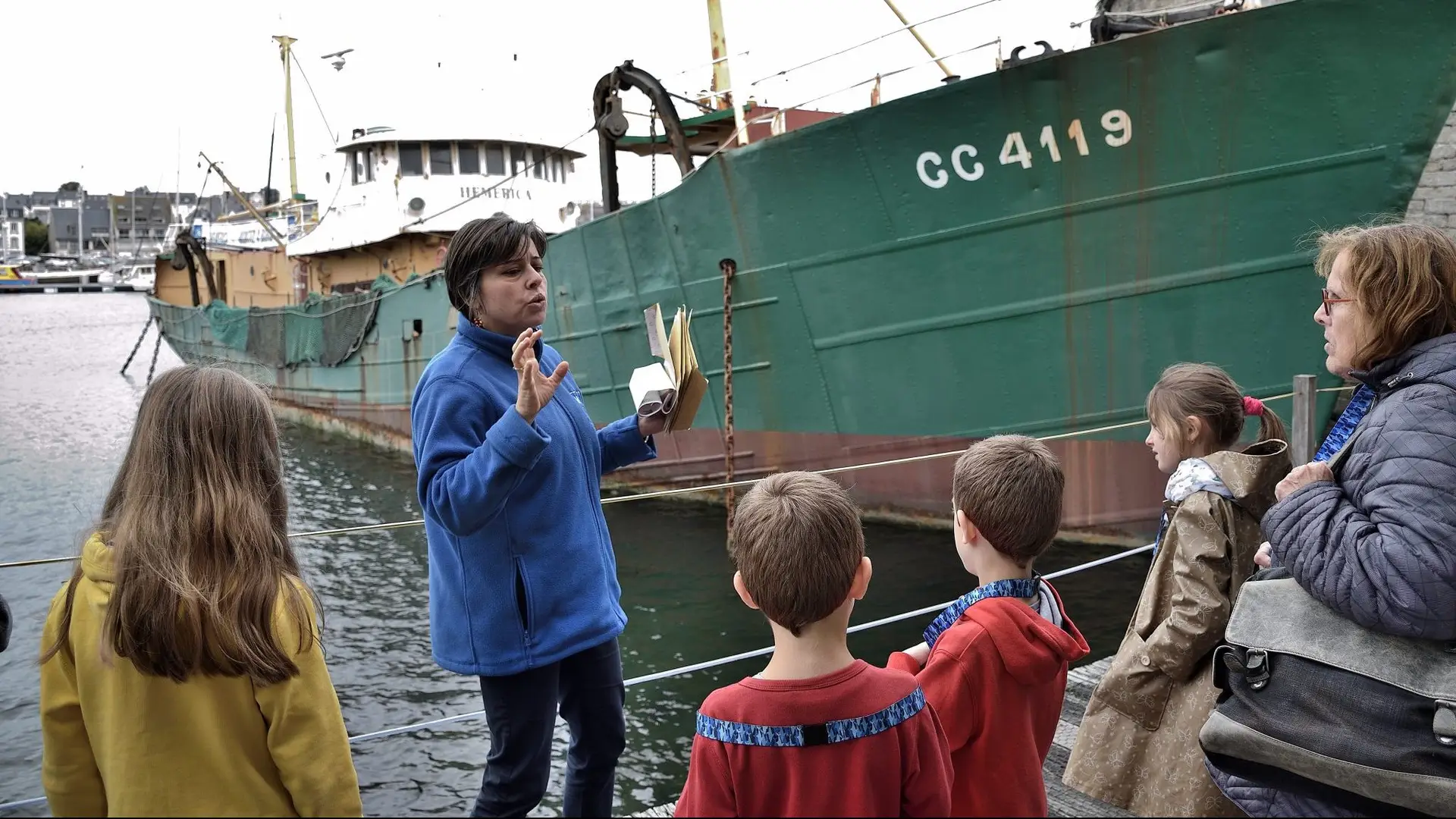 Guide expliquant l’histoire maritime à un groupe d’enfants devant un bateau de pêche, une activité idéale pour ceux qui cherchent que faire à Concarneau en 2 jours.
