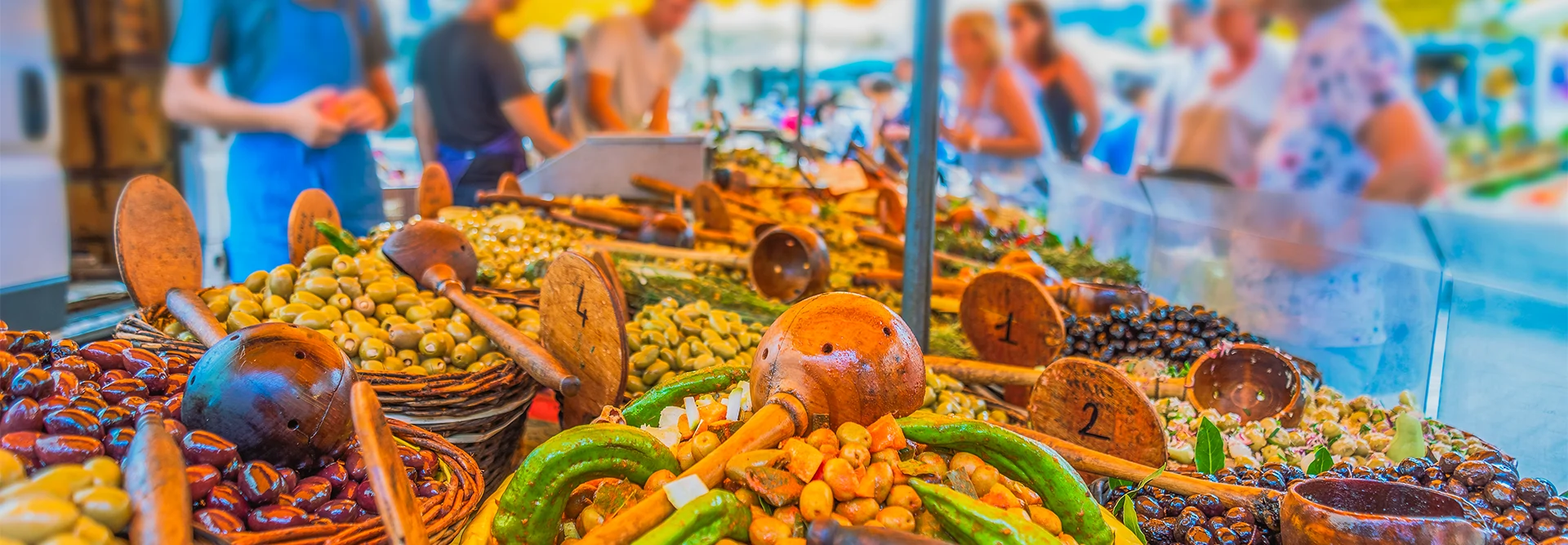 Étal coloré du marché de Concarneau avec olives, légumes frais et épices, dans une ambiance animée typiquement bretonne.